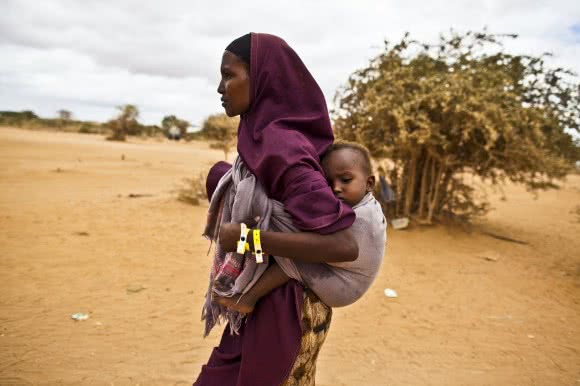 A mother arrives at Dagahaley refugee camp in Kenya with her baby. After registering, CARE provides refugees with items like tarpaulins, kitchen sets, soap, blankets and an initial food supply. Image: Evelyn Hockstein/CARE