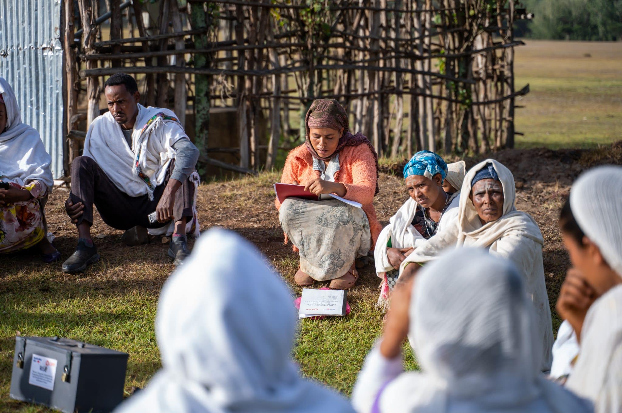 A group facilitator records members' details during a community savings and learning session in Amhara Region, Ethiopia, the locked RISE Project cash box beside her.
