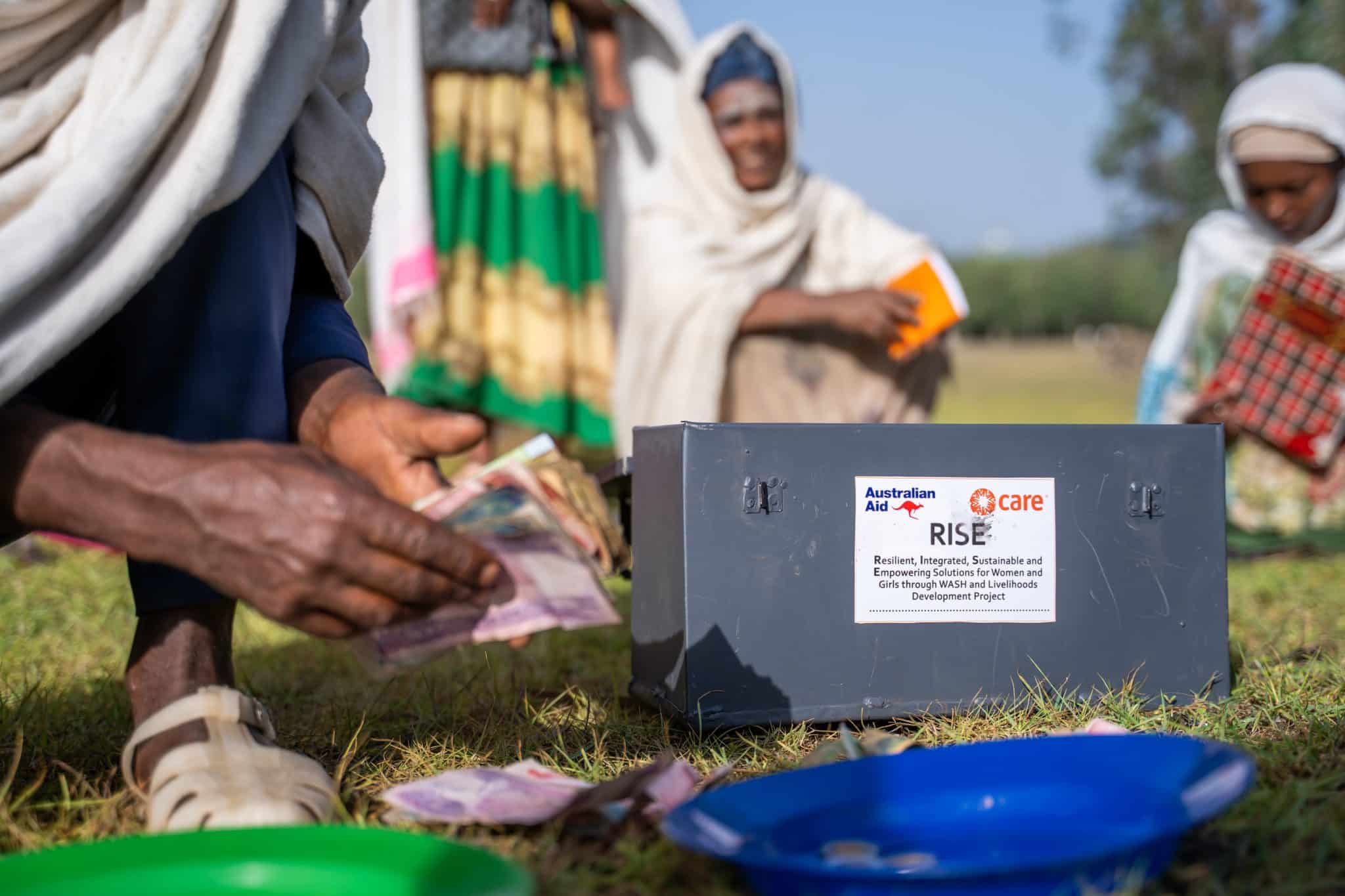 A community member counts out savings beside the group's locked RISE Project cash box in Amhara Region, Ethiopia.